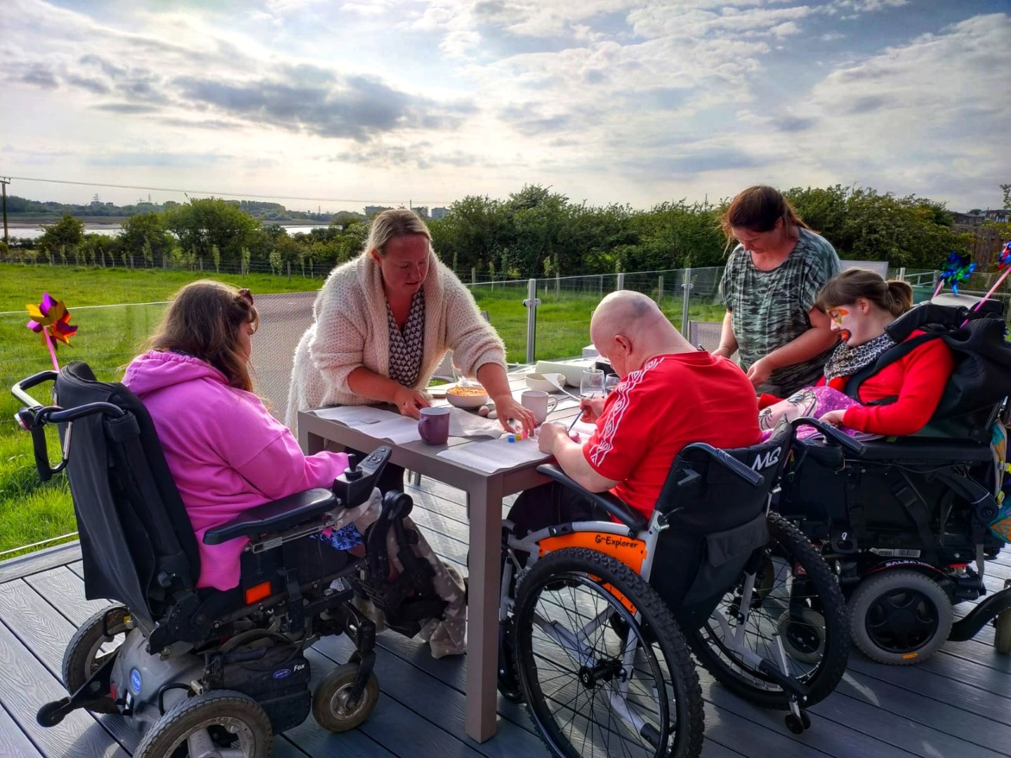 Guests in wheelchairs on decking enjoying a craft sessions. Face paints.