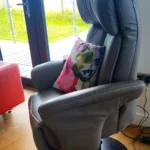 Himolla rise and recline chair at The Estuary Riverside Chalets. Grey leather with bright cushion with pink flower.
