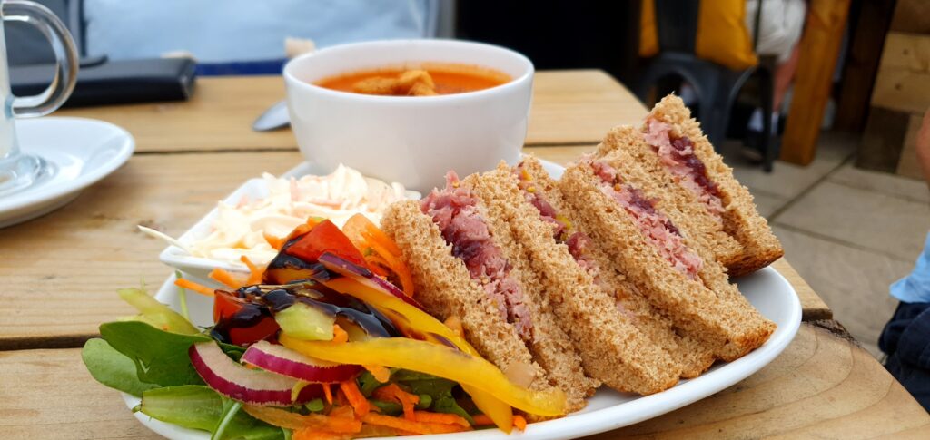 Lunch in Pipers Garstang. Ham and pickle sandwiches cut into quarters on brown bread with a side salad and coleslaw. Served with a bowl of soup in the garden.